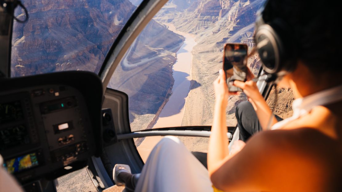 a bride inside a Las Vegas helicopter tour takes a photo on her phone while descending into the Grand Canyon