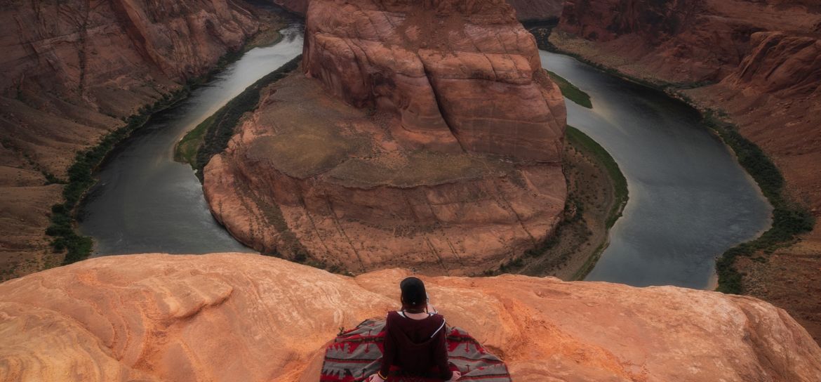 Person sitting at the edge at Page Arizona Horseshoe Bend.
