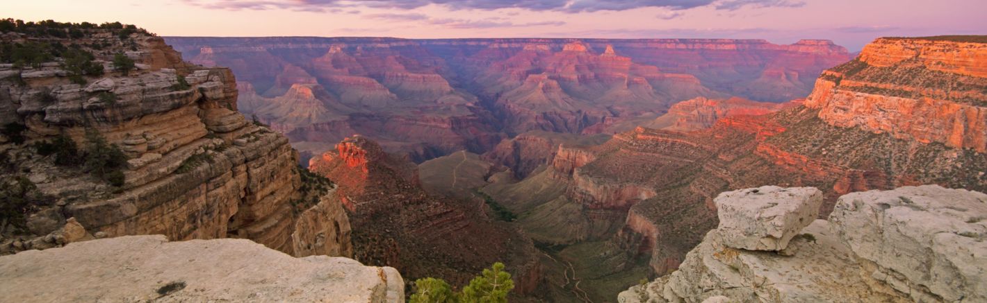 The Grand Canyon National Park with pink light from the sunset scattered across the stone walls.
