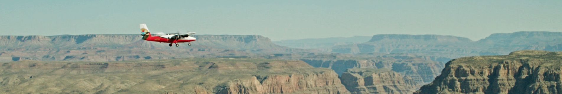 A twin-otter in GCSA livery flying over Grand Canyon