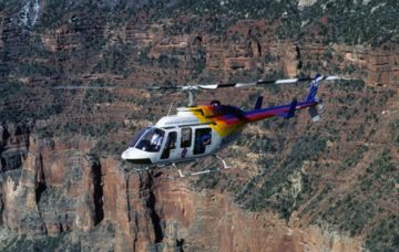 A Papillon Grand Canyon Helicopter Bell aircraft flying over the South Rim of the canyon.