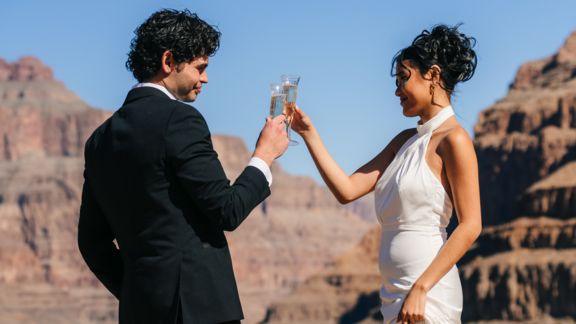 a couple toasts champagne after getting married at the bottom of the Grand Canyon