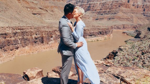 Bride and groom kissing after vows in front of Colorado River in Grand Canyon. 