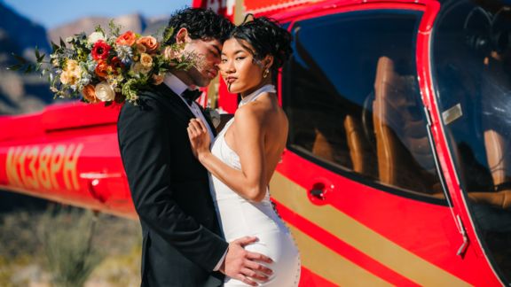 a closeup of a bride and groom kissing with a grand canyon helicopter tour landed behind them