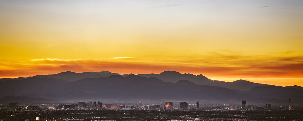 The Las Vegas Strip in front of a mountain range silhouetted by the setting sun