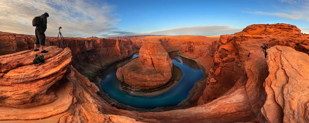 A photographer sets up a camera at the edge of Horseshoe Bend
