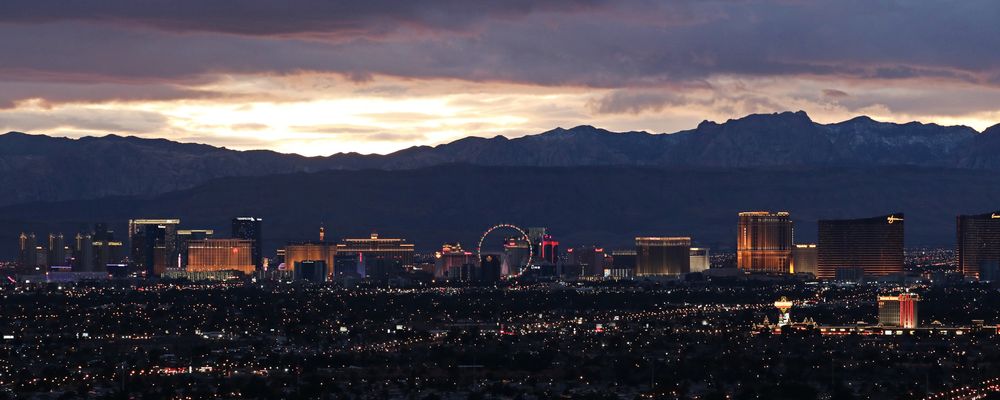 The Las Vegas Strip seen from a distance with massive mountains silhouetted in the background