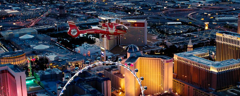 A helicopter flying over the Las Vegas Strip at night.
