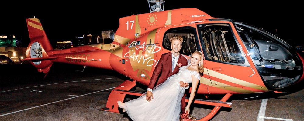 A man dips his bride in front of a Las Vegas helicopter