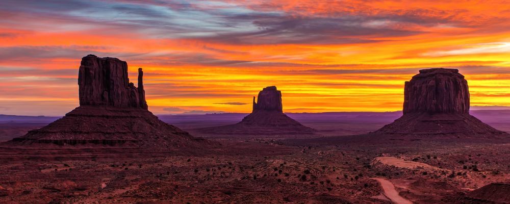 Colossal rock formations found with in Monument Valley silhouetted by a setting sun