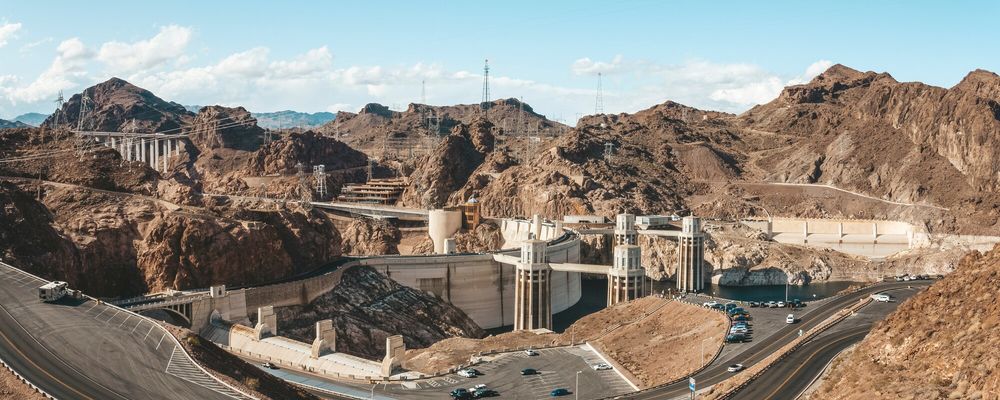 A wide shot of Hoover Dam, the nearby roadways, and the surrounding desert scenery