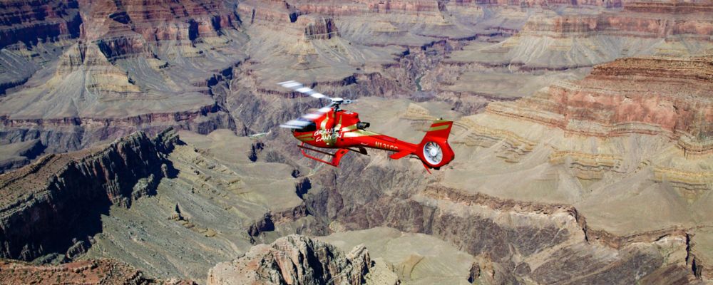 a red helicopter lands at the grand canyon air terminal after a tour over the South Rim