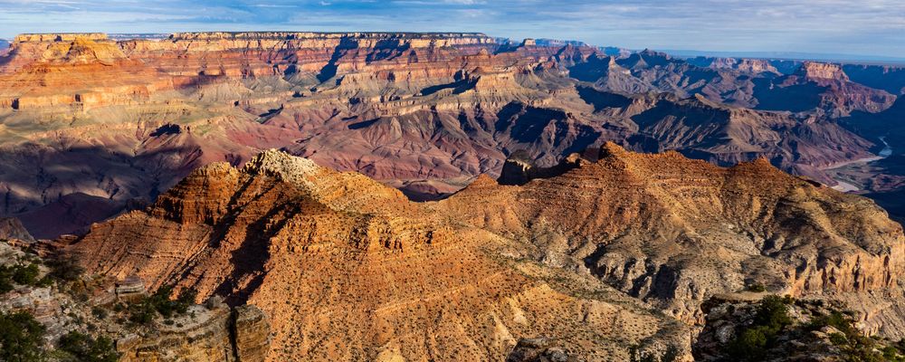 A Grand Canyon National Park viewpoint showing striped stone walls and a clear blue sky