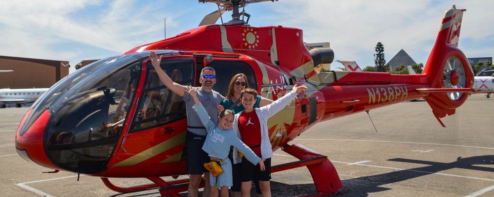 A family poses in front of a Grand Canyon helicopter