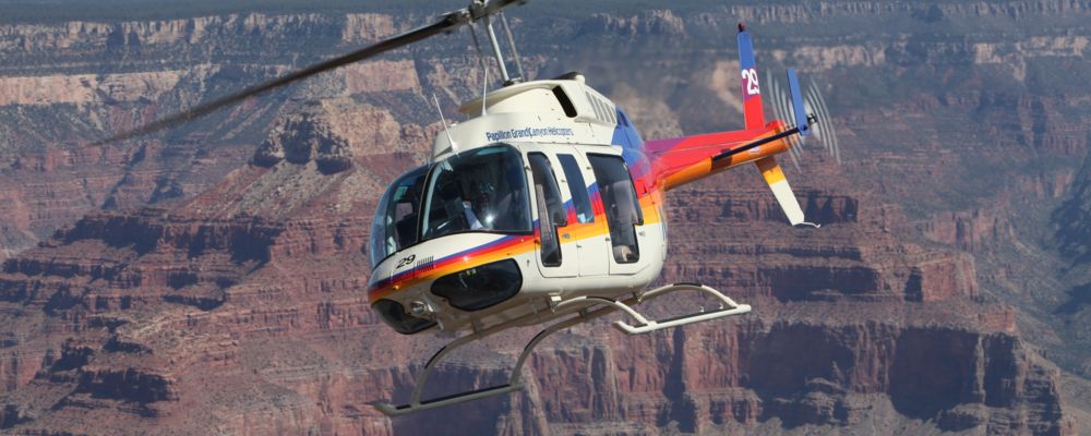 A rainbow helicopter flies over the Grand Canyon and Colorado River.