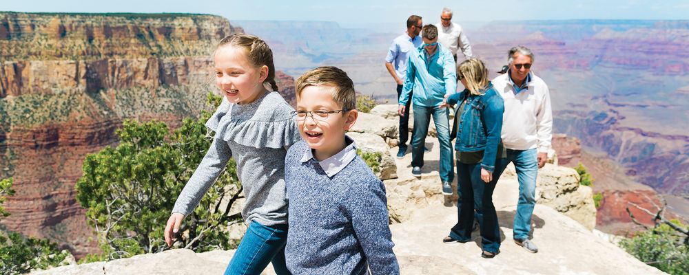 A family with children pose in front of a military-style Hummer vehicle at the Grand Canyon