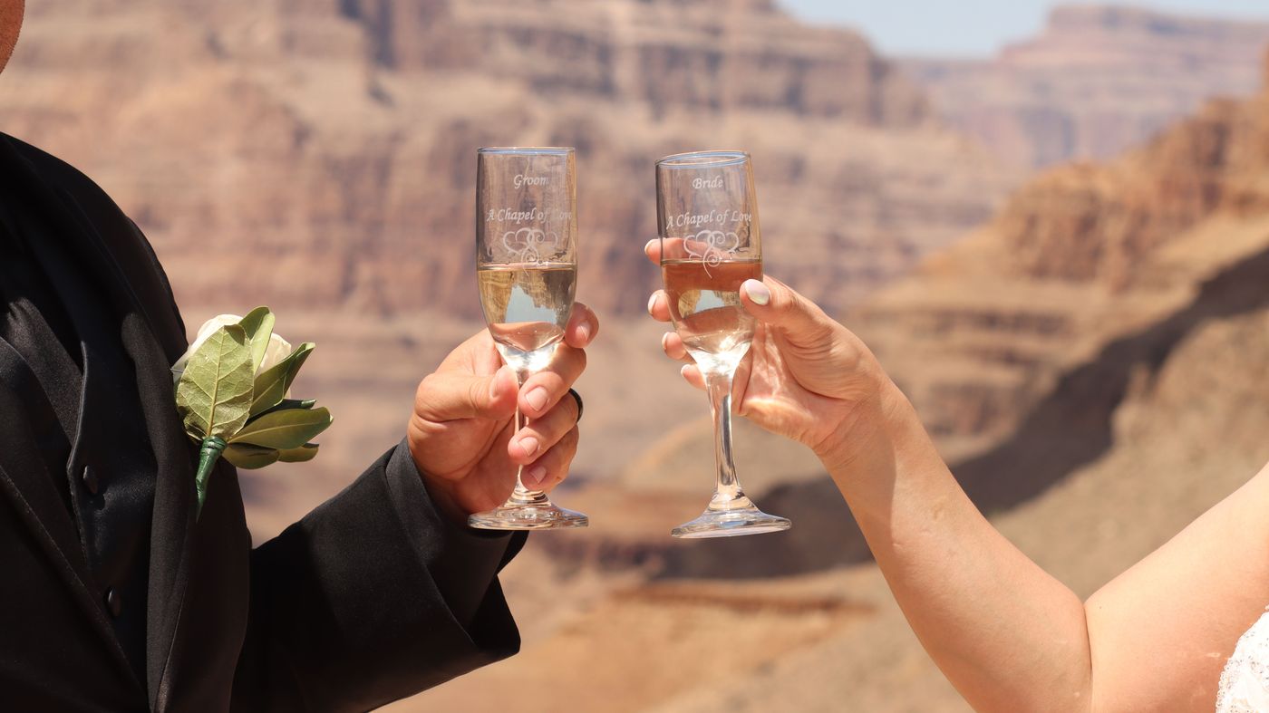 Bride and groom cheers with champagne flute during wedding at Grand Canyon West Rim.