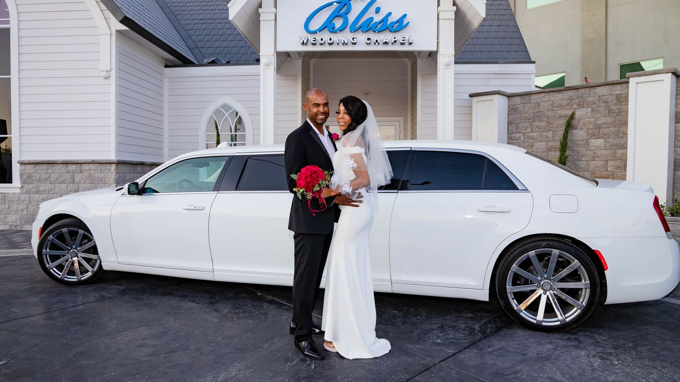 Newly weds in front of Bliss Chapel with a white limousine.