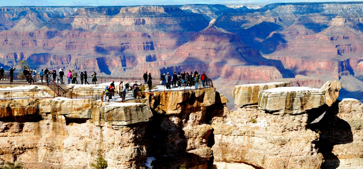 a large group of people stand atop a Grand Canyon National Park lookout point
