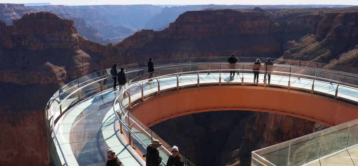 guests at the Grand Canyon West stand atop the Skywalk bridge looking out at canyon scenery