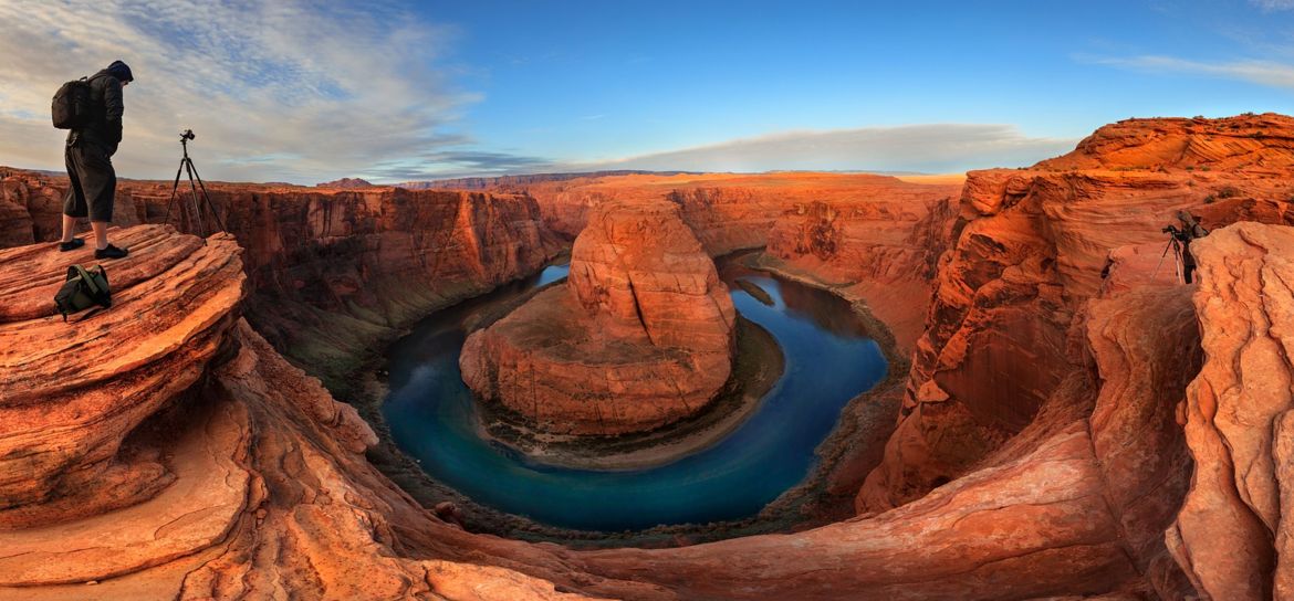 a wide shot of Horseshoe Bend in Page, AZ where a photographer stands on the very edge