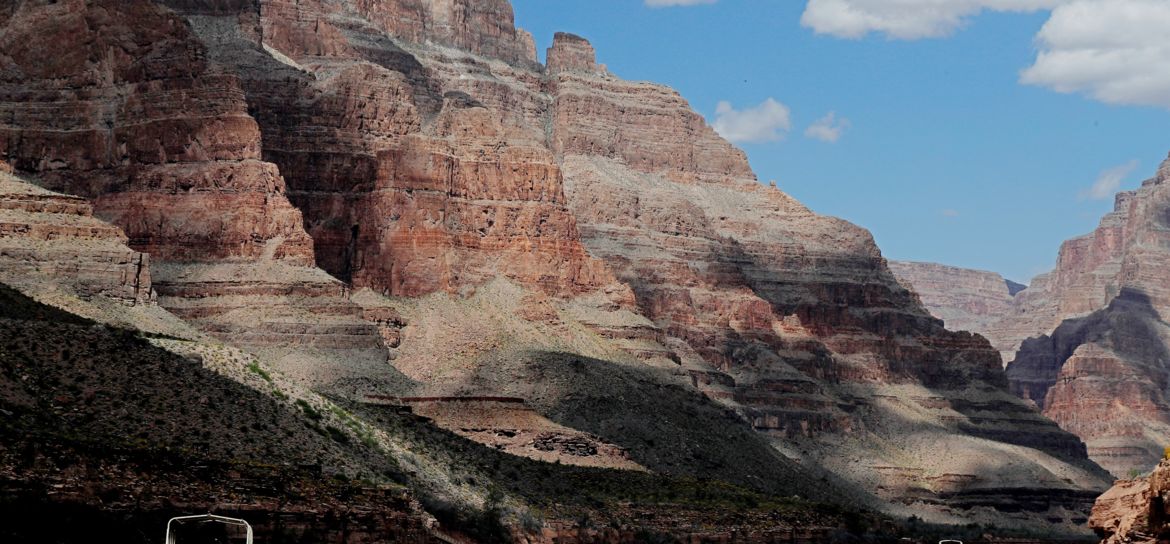 a pontoon boat floating down the Colorado River between the walls of the Grand Canyon West