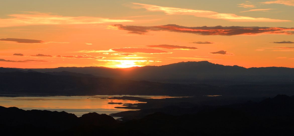 lake mead and surrounding mountains silhouetted by the las vegas sunset