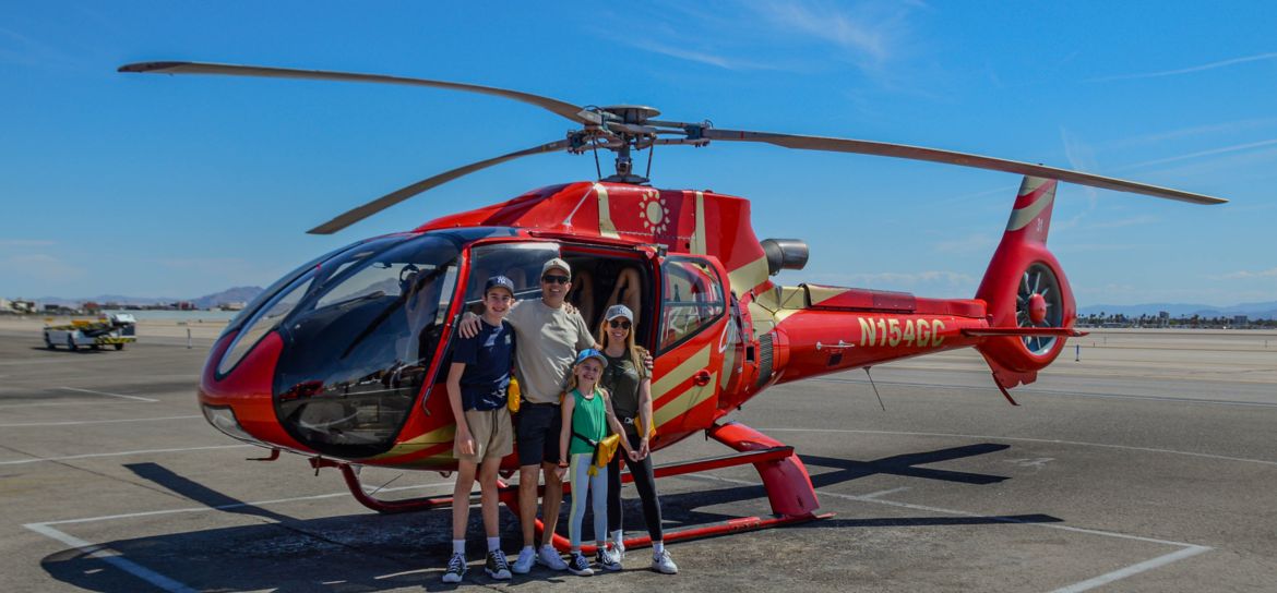 Family Helicopter Tour a family of four poses on the Las Vegas air terminal tarmac in front of a sightseeing helicopter