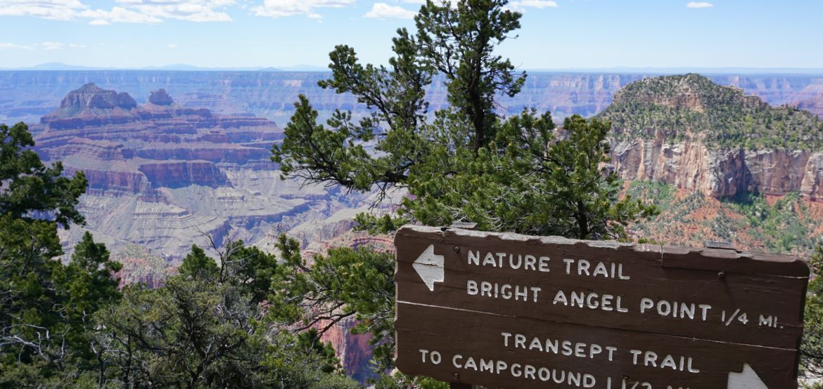 a sign notating nearby hiking trails at the edge of the grand canyon