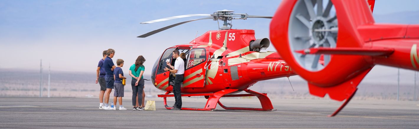 passengers board a red sightseeing helicopter on the tarmac at a Las Vegas air terminal