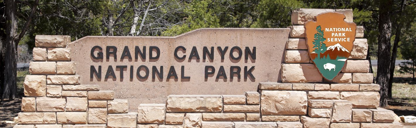 the entrance sign for the Grand Canyon National Park in bright sunlight