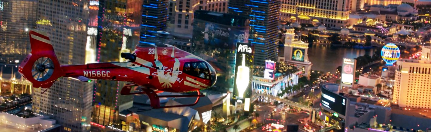 a red helicopter flies over the las vegas strip casinos at night