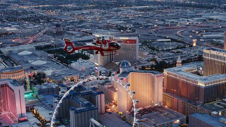 a red helicopter flies past the High Roller Observation Wheel on the Las Vegas Strip