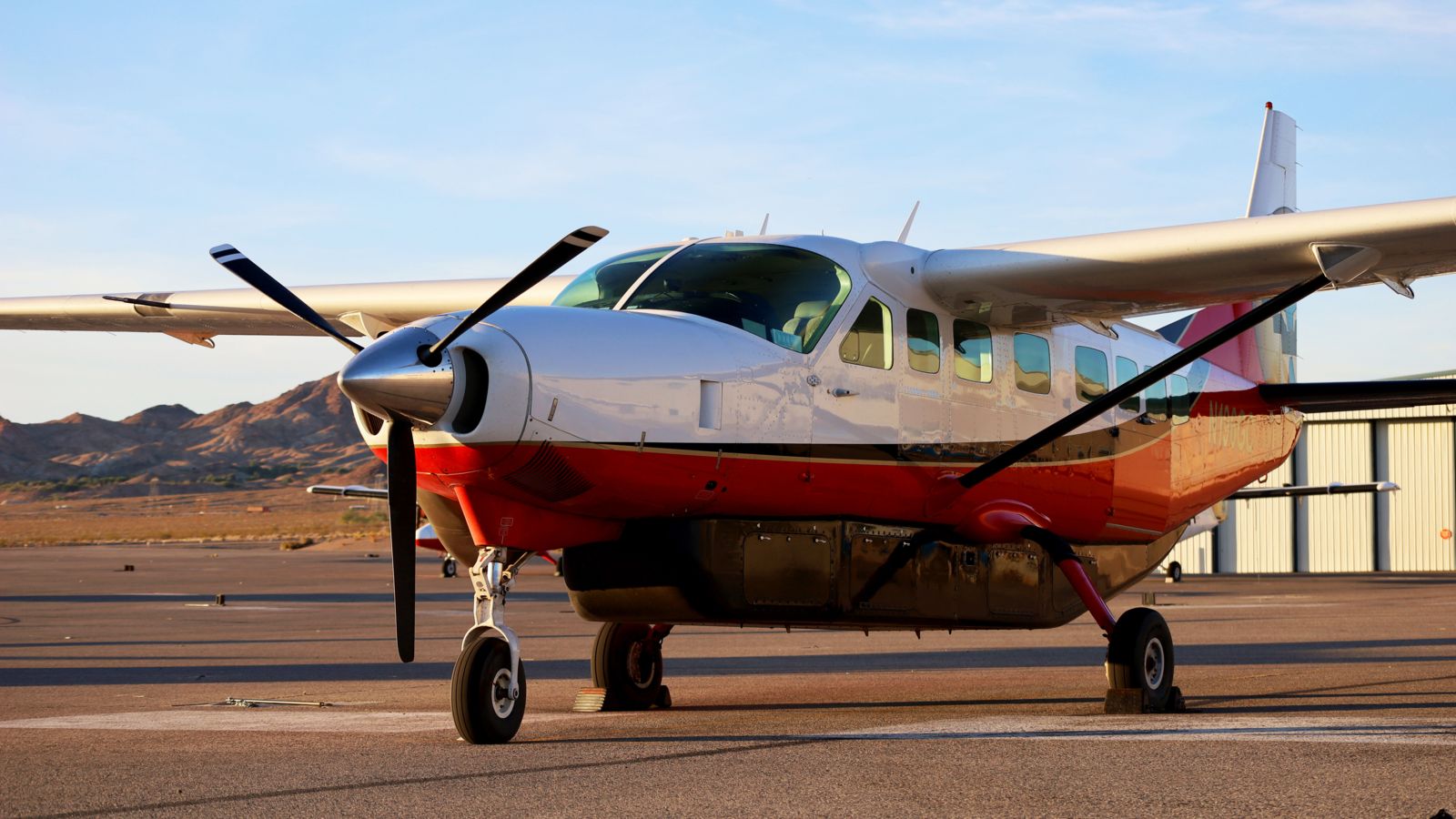 A Cessna sightseeing airplane parked on the tarmac at sunset
