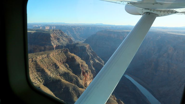 A view of the Grand Canyon West Rim seen through the window from inside a Grand Canyon airplane tour.