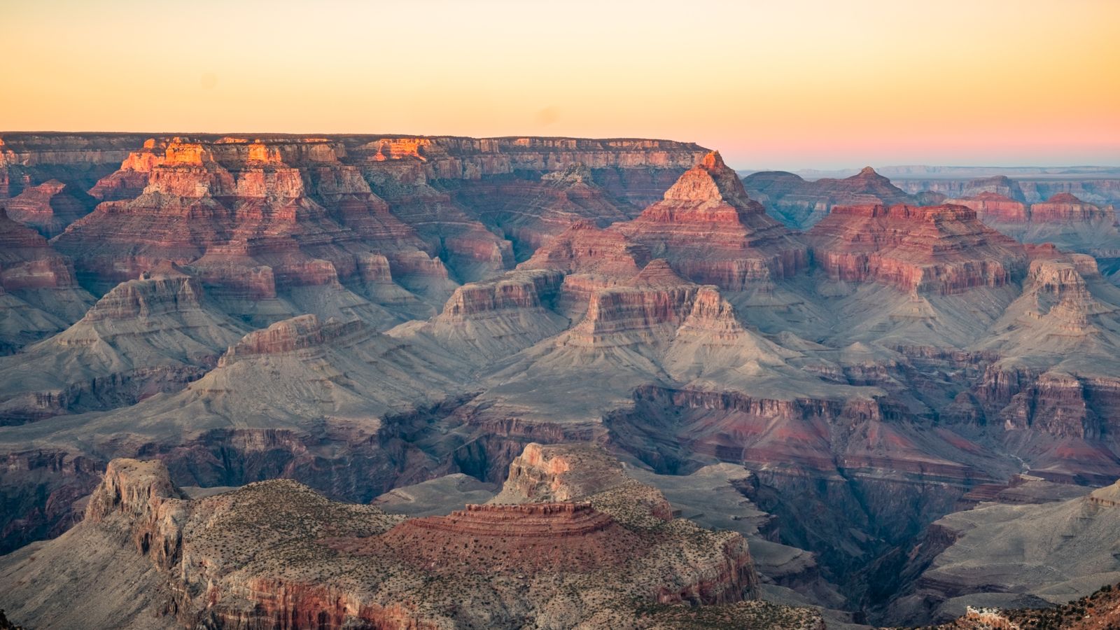 a grand canyon south rim lookout illuminated pink by the sunset