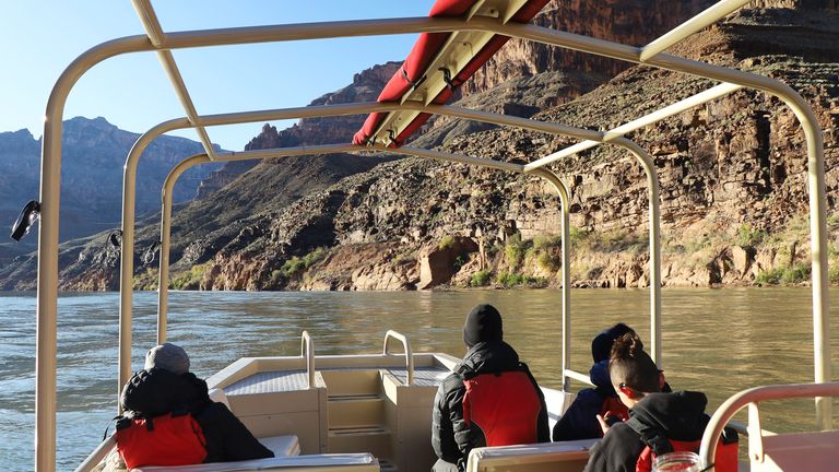 Tourists on a pontoon boat on the Colorado River with the Grand Canyon walls on either side