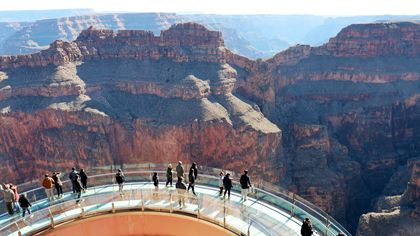 an aerial view of the Skywalk Bridge where visitors stand on a glass walkway over the Grand Canyon West