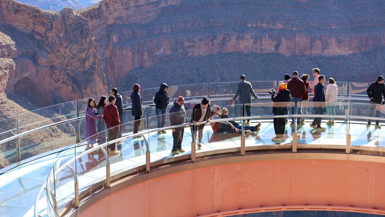 several Grand Canyon visitors get their photos taken on top the Skywalk Bridge