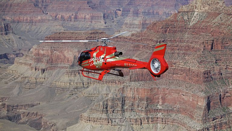 Red EC130 helicopter flying over Grand Canyon West