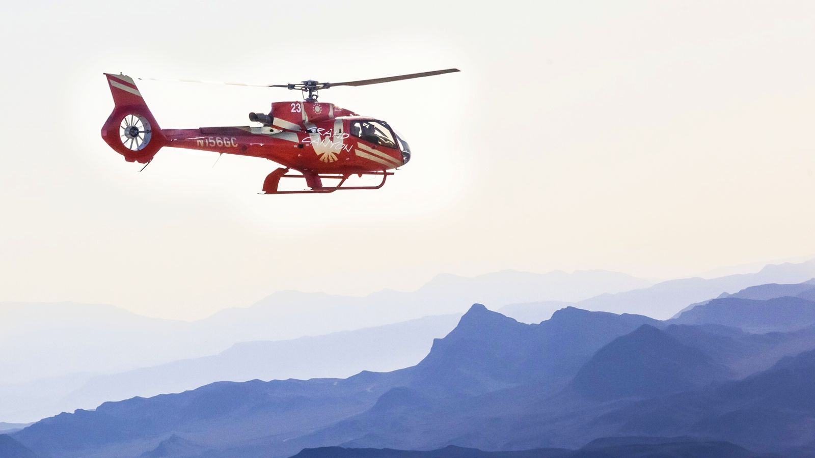 a helicopter tour in flight toward the Grand Canyon with a mountain range in the background