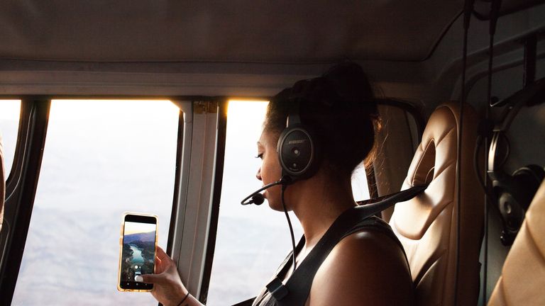 Women taking photos with phones on a helicopter tour to the Grand Canyon