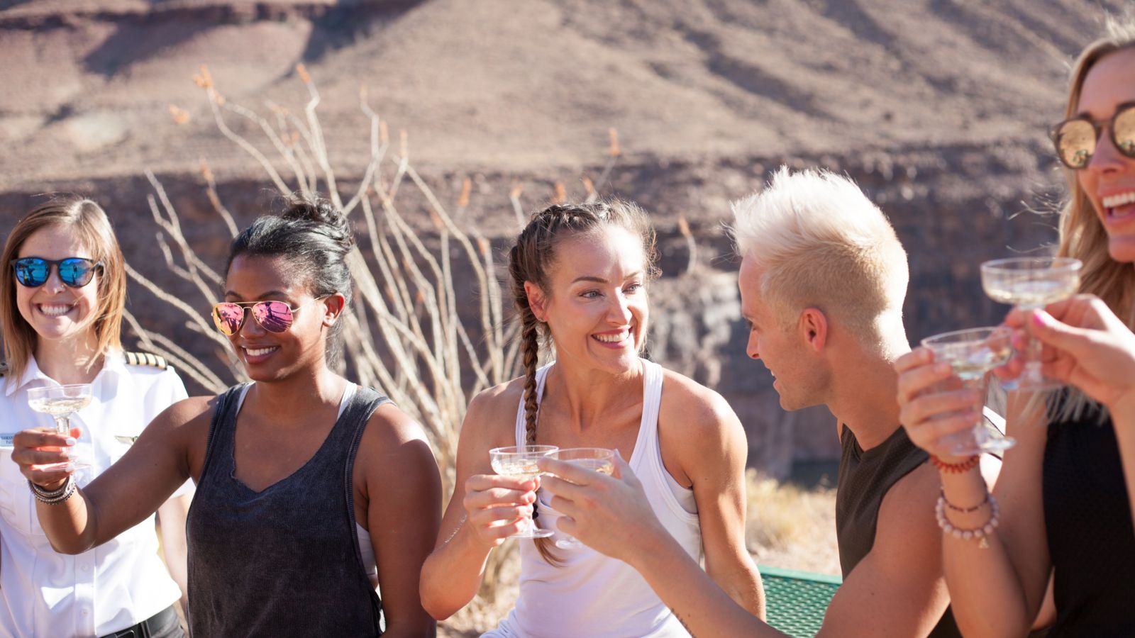a group of helicopter tour passengers at the bottom of the Grand Canyon West toasting champagne
