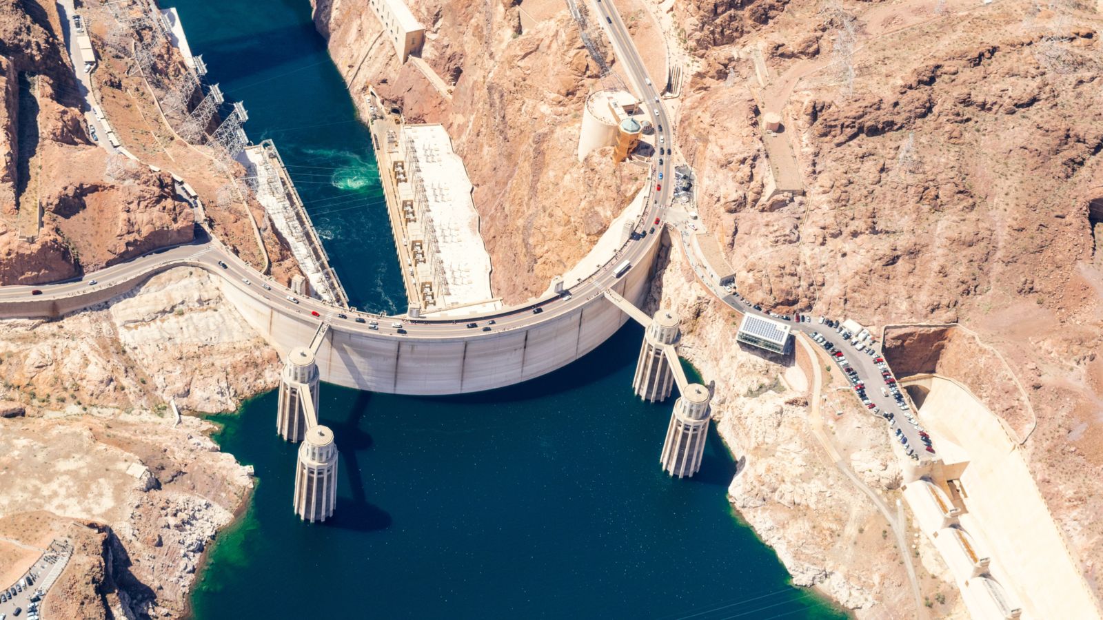an aerial view of the O'Callaghan-Tillman Memorial Bridge and the Colorado River and dam water beneath it surrounded by desert landscape