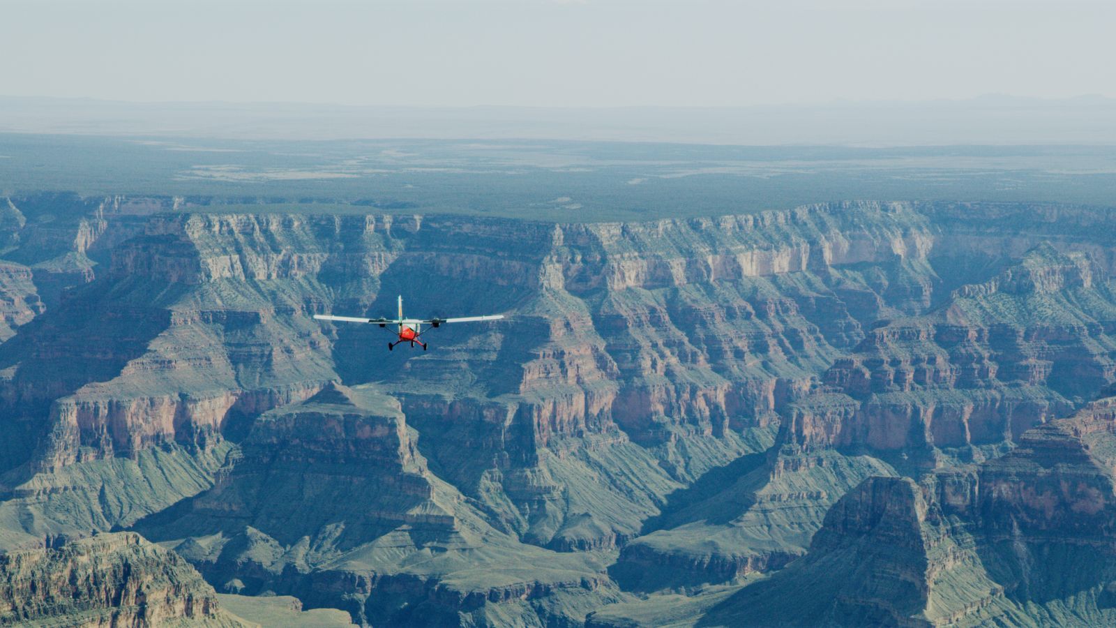 a twin otter touring airplane flies over the grand canyon south