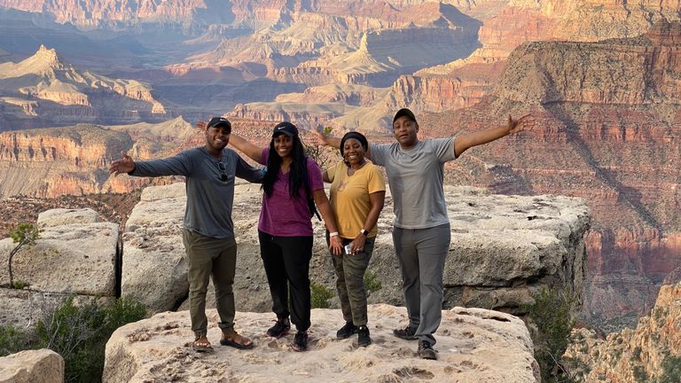 a family of four poses smiling at the edge of the Grand Canyon National Park