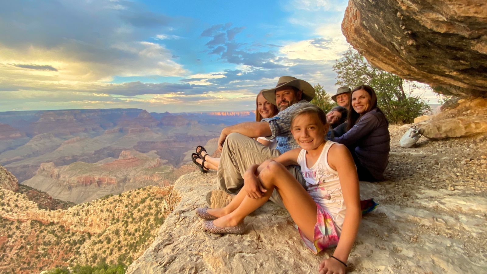 a family poses sitting on a rock formation at the grand canyon