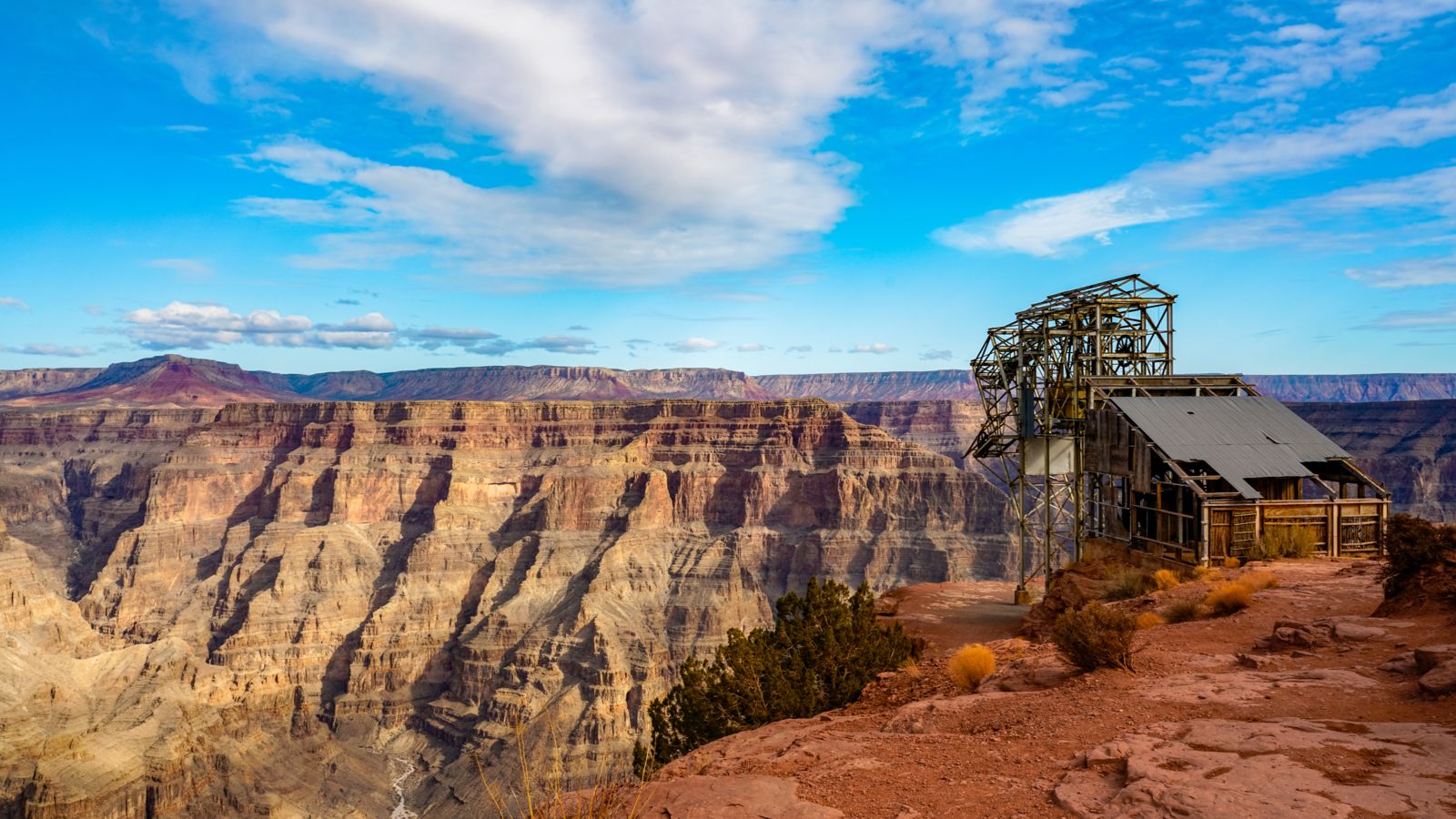 Bright sunny day with some clouds at Grand Canyon West Rim standing on the edge with old abandoned guano mine at Guano Point