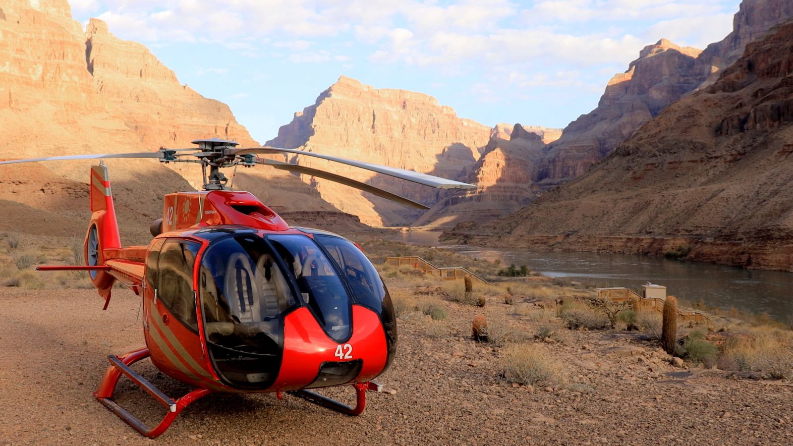 A red EC130 Helicopter landed at the bottom of the canyon next to the entrance to the pontoon boat ramp at Grand Canyon West