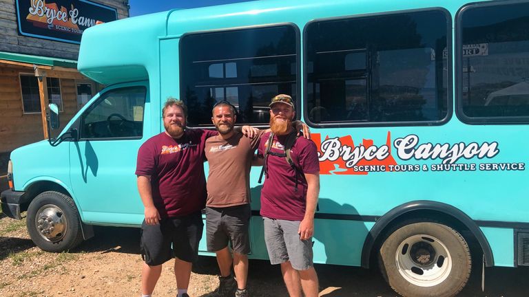 three men pose in front of a Bryce Canyon tour vehicle